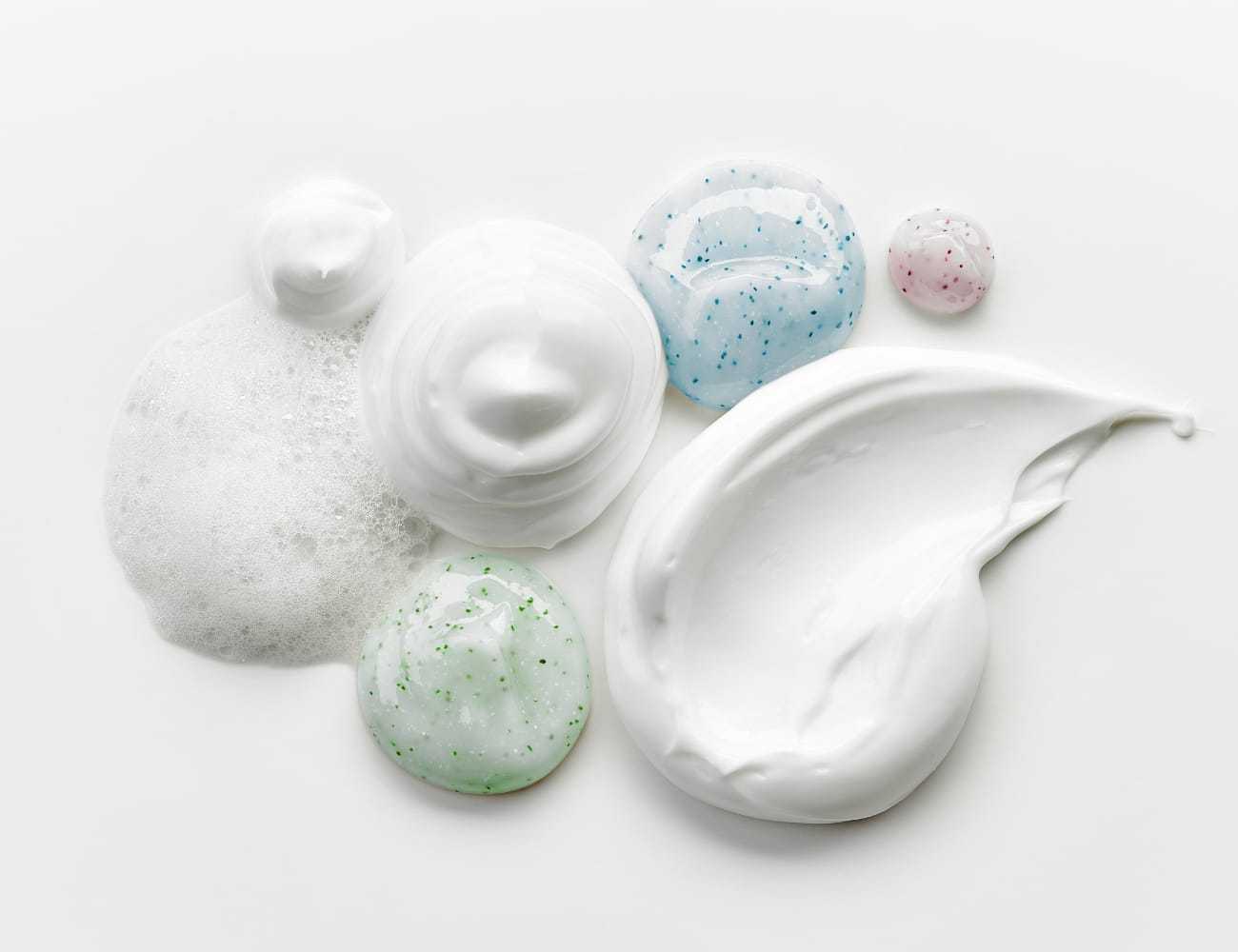 Skincare products swirled and dolloped on a white surface, featuring various textures.