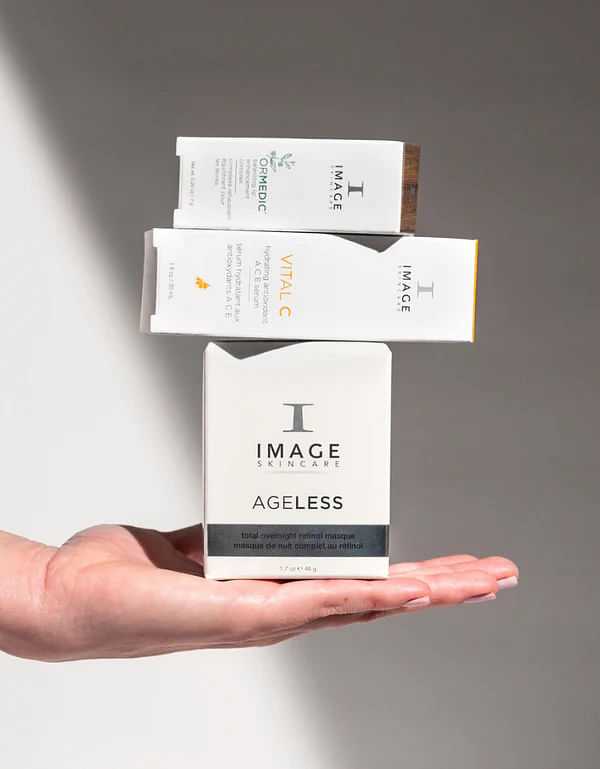 Hand presenting three skincare product boxes against a neutral background.