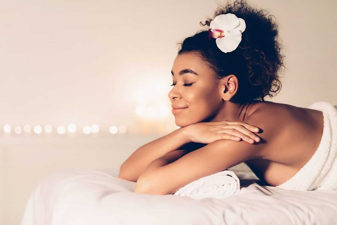 Woman relaxing at a spa with candles in the background.